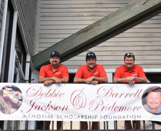 Pridemore scholarship event with three Smoky Hill Automotive employees and banner